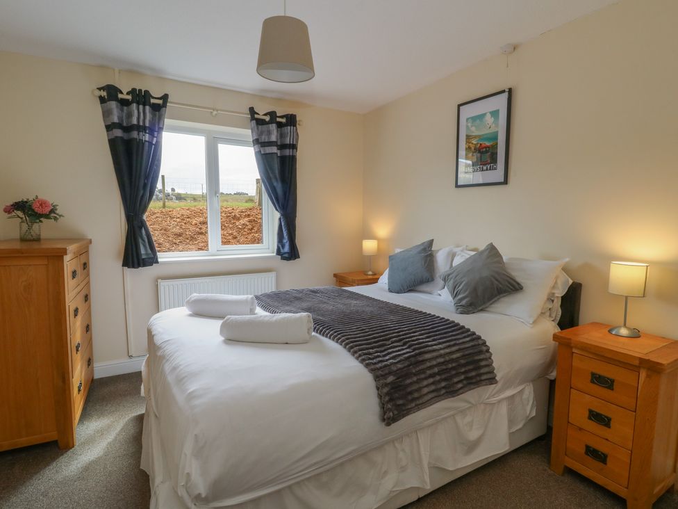 A bedroom with a double bed and window at Glanyrafon Bungalow in St Harmon