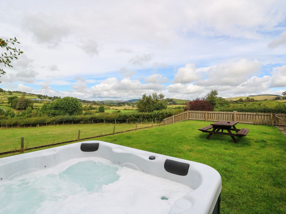 An outdoor area with a hot tub and picnic table at Glanyrafon Bungalow St Harmon