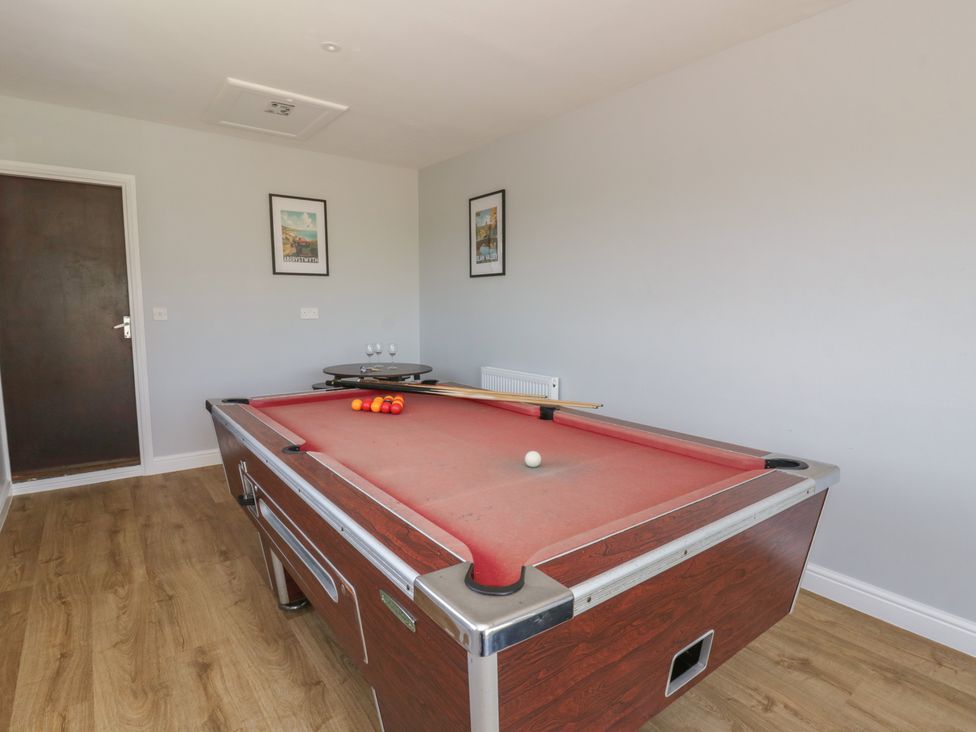 A games room with a pool table and cue sticks at Glanyrafon Bungalow in St Harmon