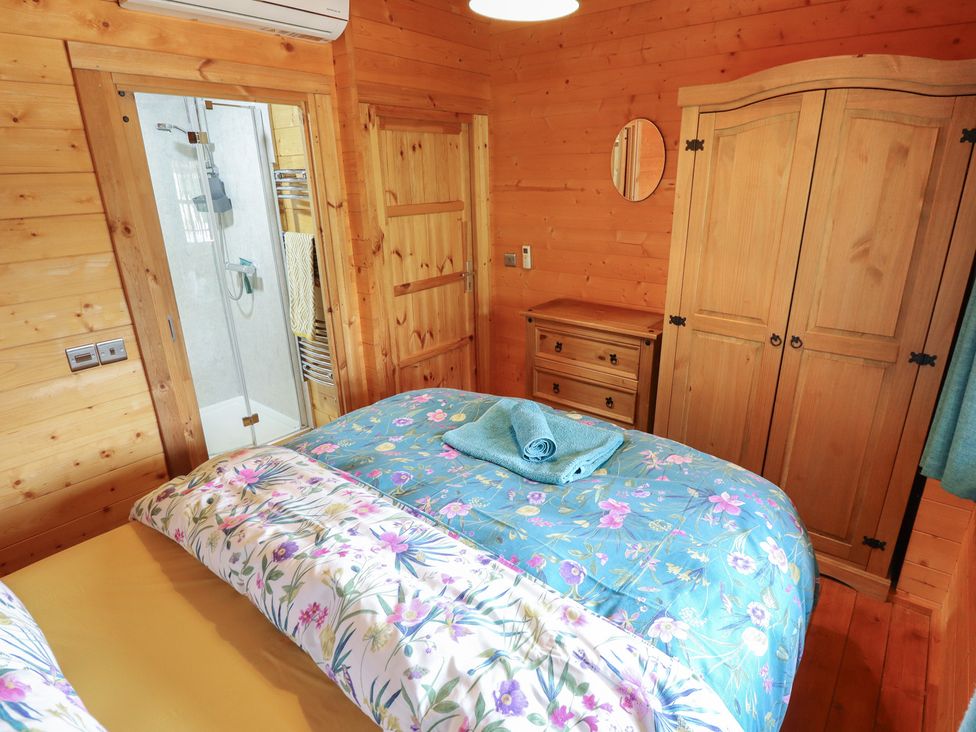A bedroom with a bed and shower at Tythe Lodge – Hot Tub Retreat in Rural Lincolnshire | Family-Friendly Lodge Near Heckington