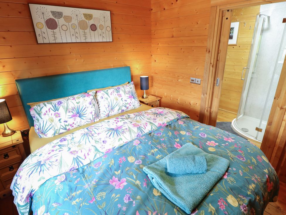 A bedroom with a double bed and a shower at Tythe Lodge – Hot Tub Retreat in Rural Lincolnshire | Family-Friendly Lodge Near Heckington