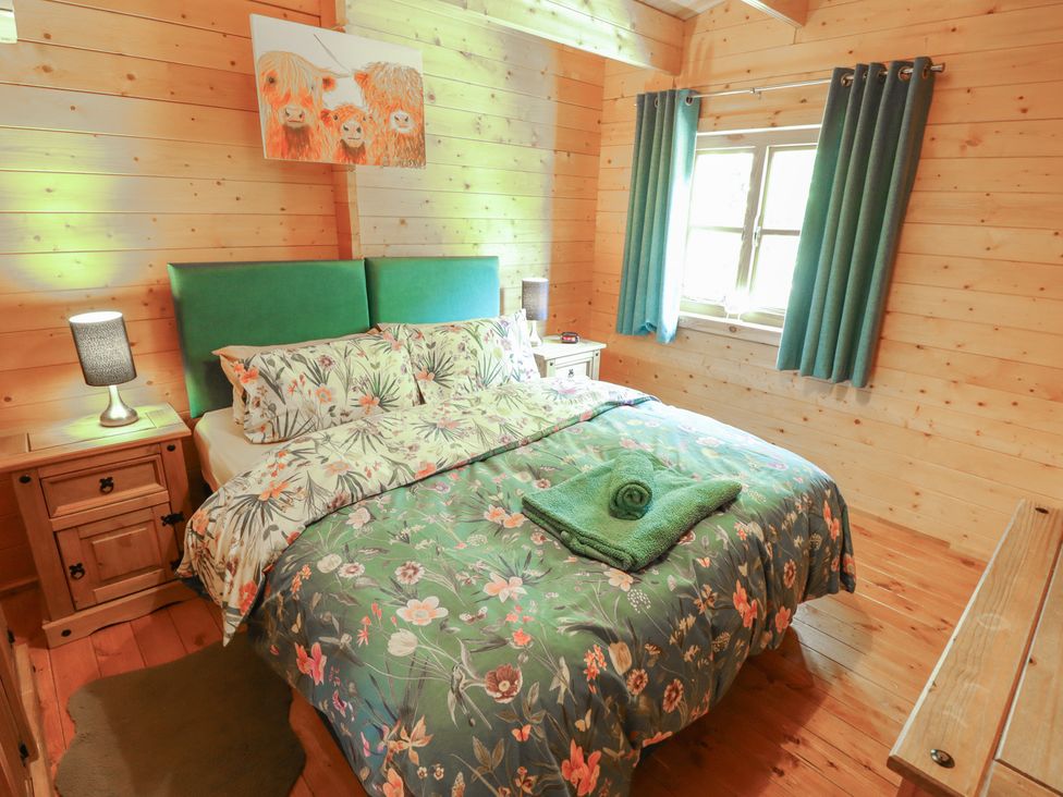 A bedroom with a bed, bedside table and window at Tythe Lodge – Hot Tub Retreat in Rural Lincolnshire | Family-Friendly Lodge Near Heckington