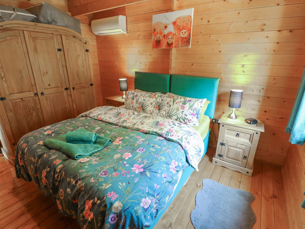 A bedroom with a bed and a bedside table at Tythe Lodge – Hot Tub Retreat in Rural Lincolnshire | Family-Friendly Lodge Near Heckington