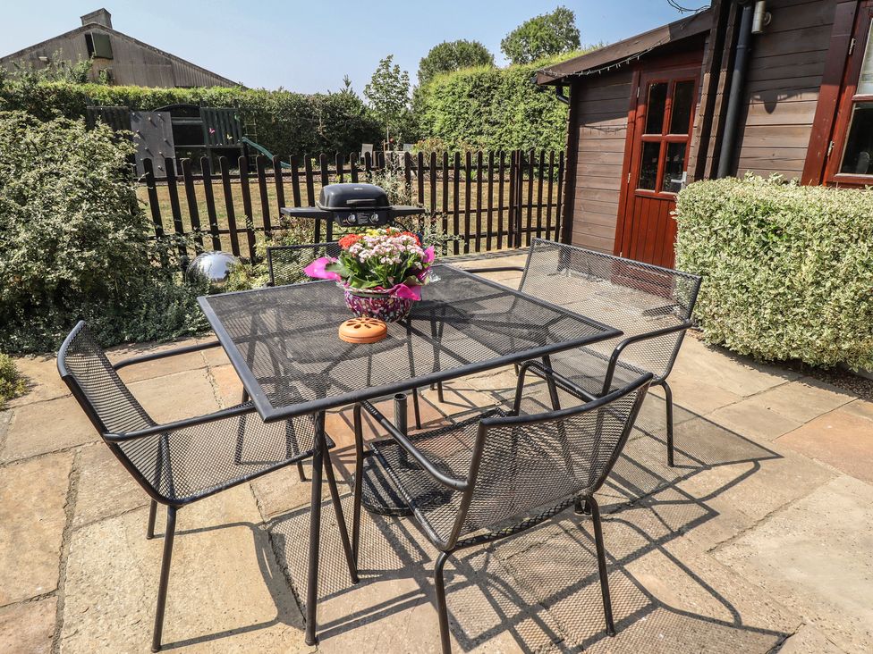 A patio with a table and chairs at Tythe Lodge – Hot Tub Retreat in Rural Lincolnshire | Family-Friendly Lodge Near Heckington