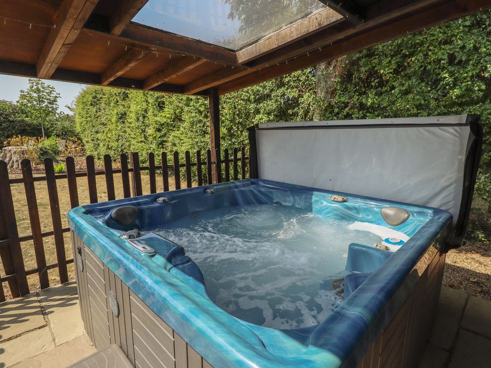 A hot tub with a cover in an outdoor area at Tythe Lodge – Hot Tub Retreat in Rural Lincolnshire | Family-Friendly Lodge Near Heckington