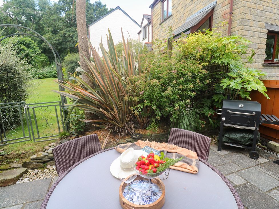 An outdoor area with a table, plants, and a barbecue at Tranquility in Falmouth