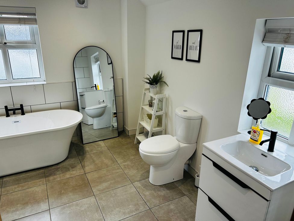 A bathroom with a bathtub, mirror, and toilet at Trearddur View in Treaddur Bay