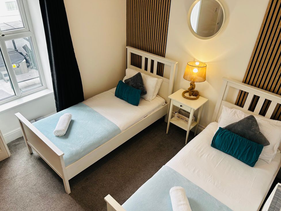 A bedroom with two single beds and a nightstand at Trearddur View in Treaddur Bay