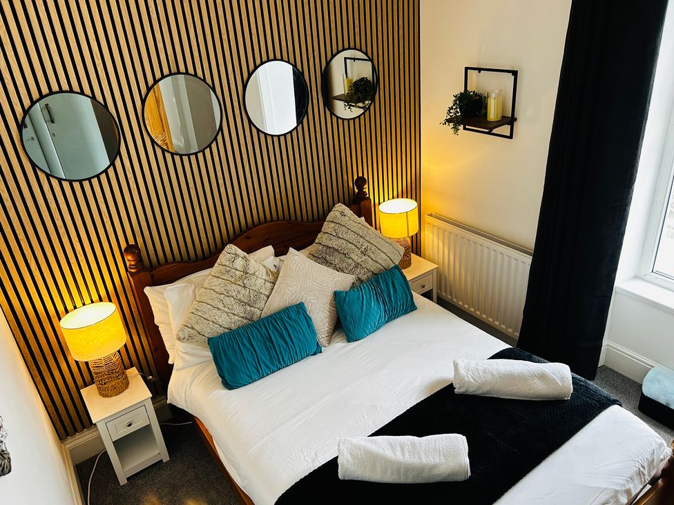 A bedroom with a bed and mirrors on the wall at Trearddur View in Treaddur Bay
