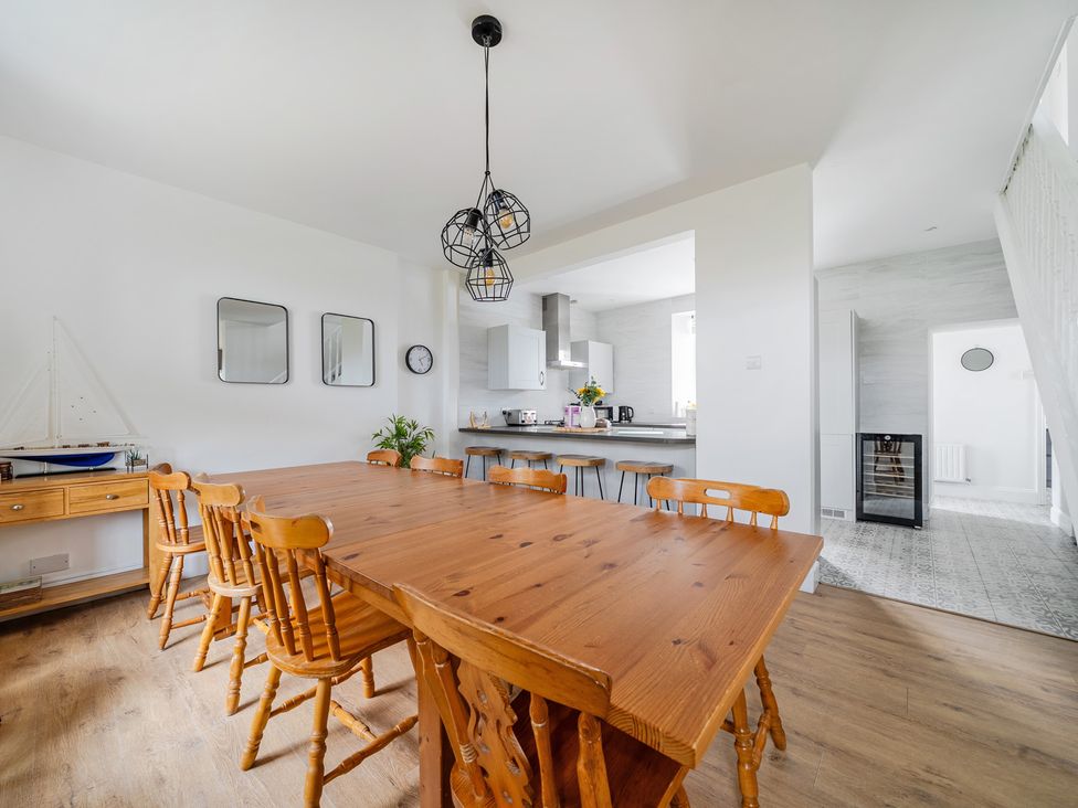 A dining room with a wooden table and chairs at Trearddur View in Treaddur Bay