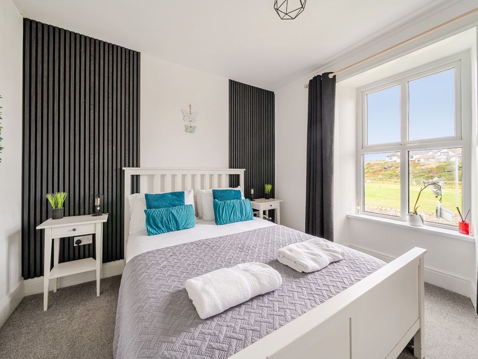 A bedroom with a bed and nightstands at Trearddur View in Treaddur Bay