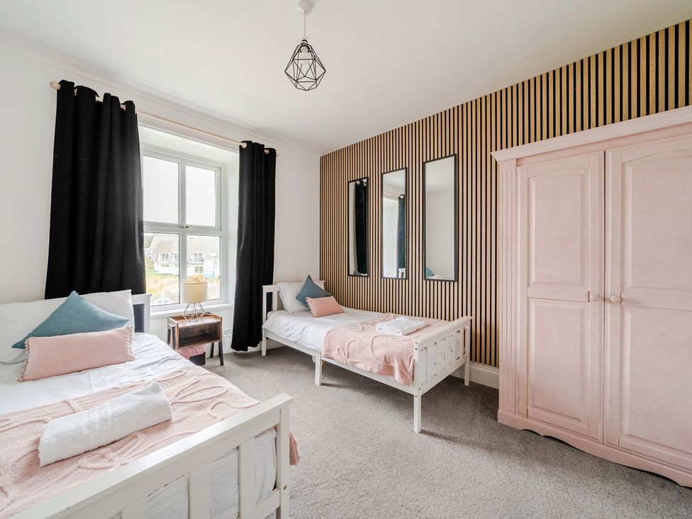 A bedroom with two beds and a wardrobe at Trearddur View in Treaddur Bay