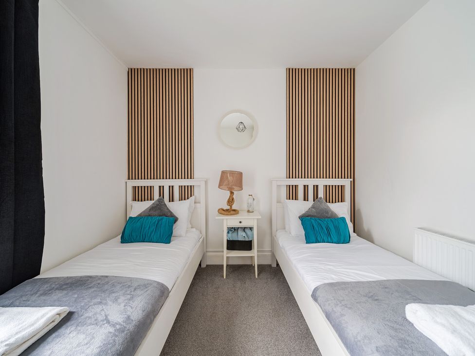 A bedroom with two single beds and a bedside table at Trearddur View in Treaddur Bay