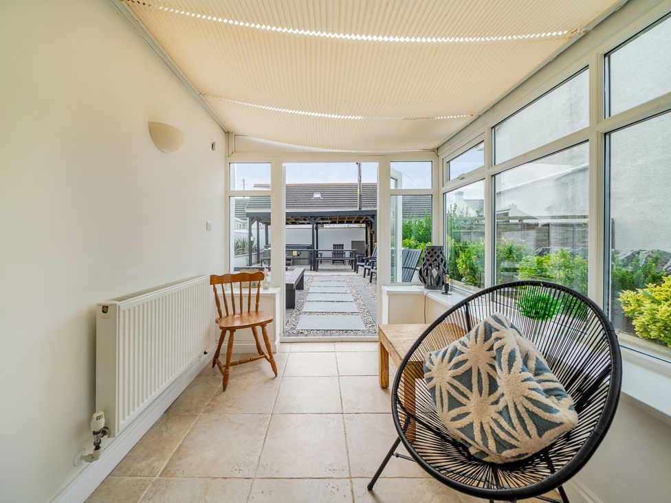 A conservatory with a chair and table at Trearddur View, Treaddur Bay