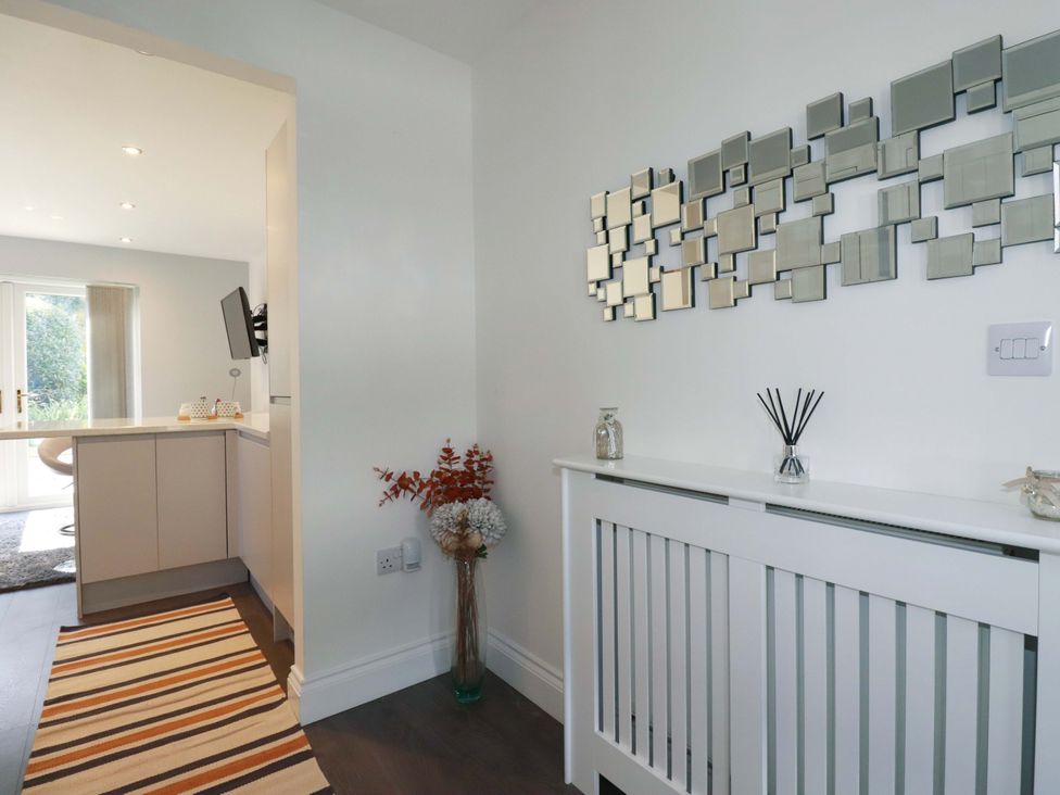 A hallway with a mirror and radiator cover at Little Pippin in Carlyon Bay near St Austell