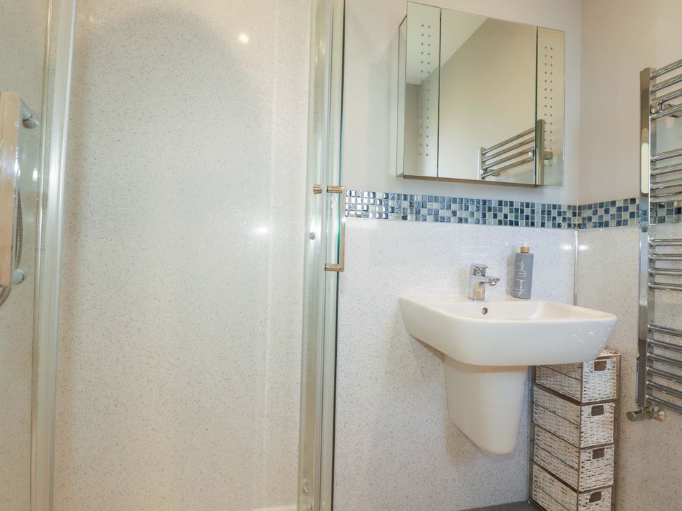 A bathroom with a shower and sink at Little Pippin in Carlyon Bay near St Austell