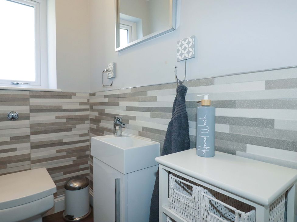 A bathroom with toilet, sink, and hand wash at Little Pippin Carlyon Bay near St Austell