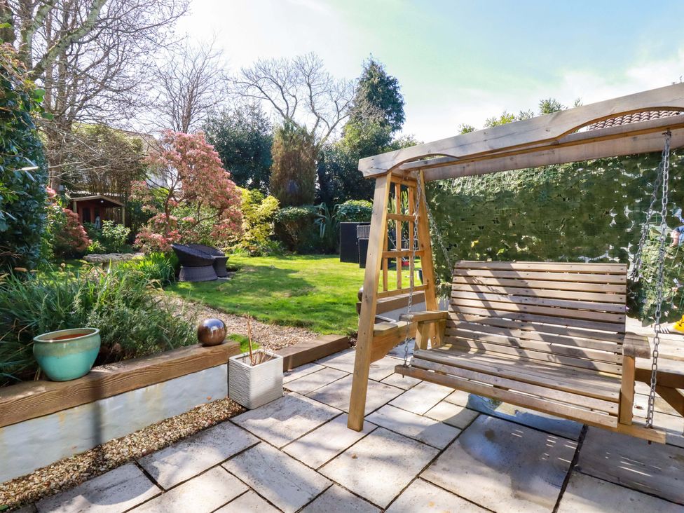 A garden with a swing and plants at Little Pippin in Carlyon Bay near St Austell