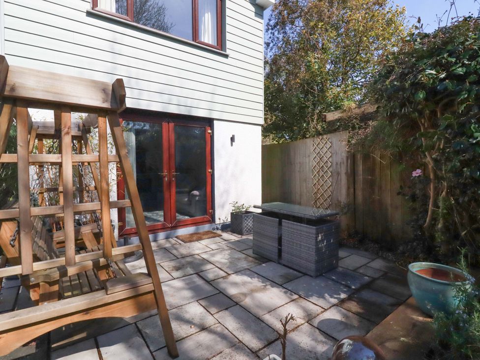 A garden with a swing and paving stones at Little Pippin in Carlyon Bay near St Austell