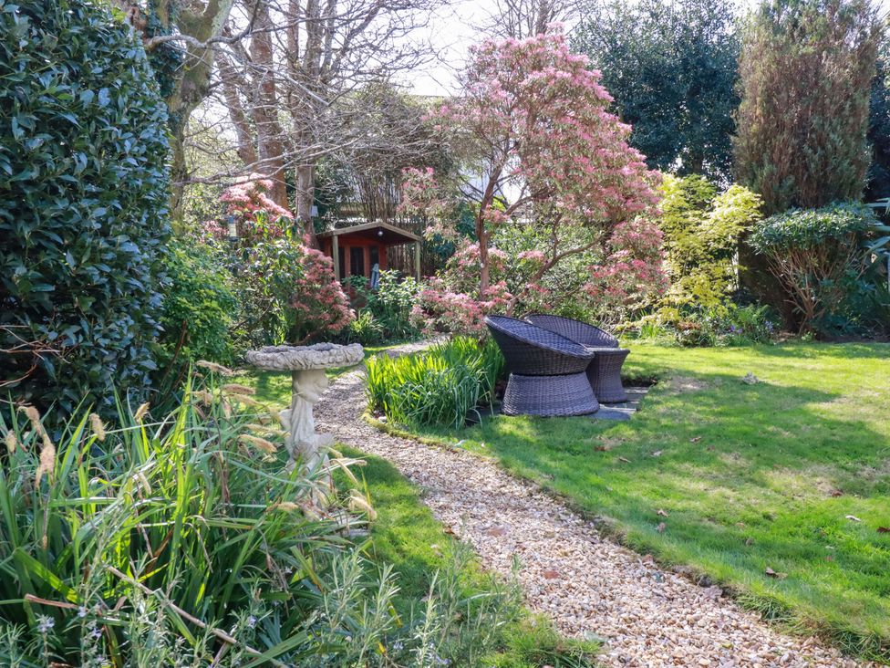 A garden with chairs and a birdbath at Little Pippin in Carlyon Bay near St Austell