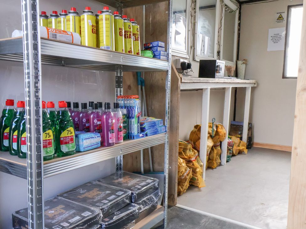 A storage room with shelves containing cleaning products and various items at Stable Cottage in Staintondale