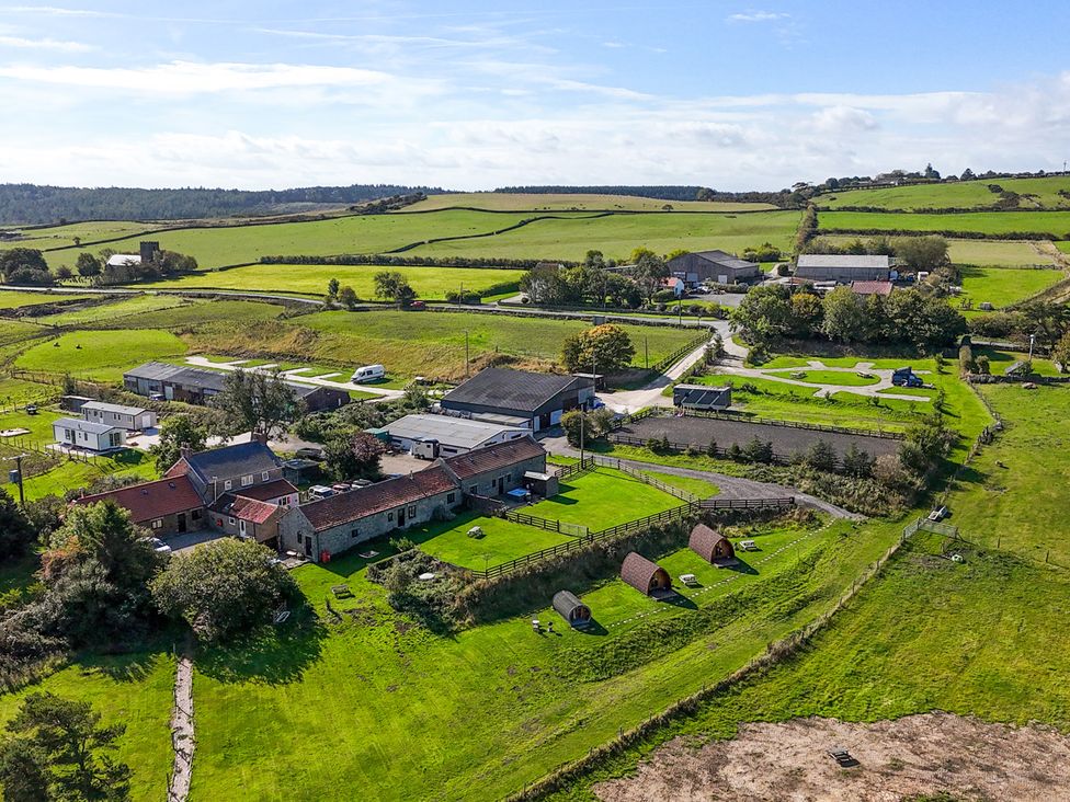An aerial view of farmland with buildings and a road at Stable Cottage in Staintondale