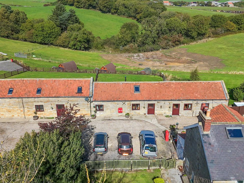 An outdoor area with cottages and parked cars at Stable Cottage Staintondale