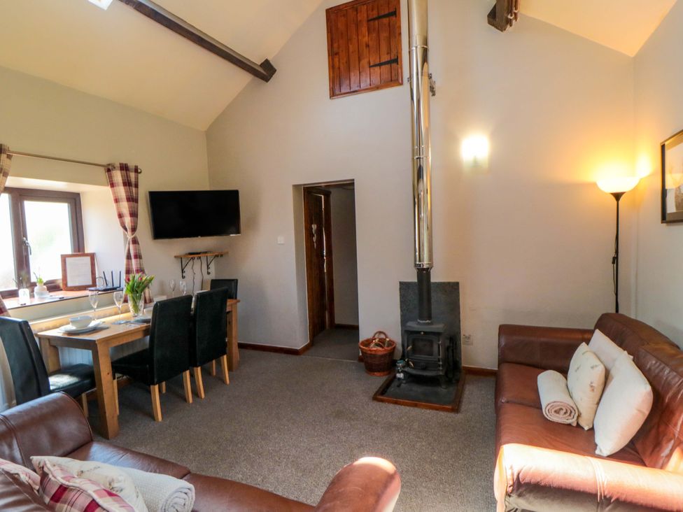 A living room with a dining table and a wood stove at Stable Cottage in Staintondale near Burniston