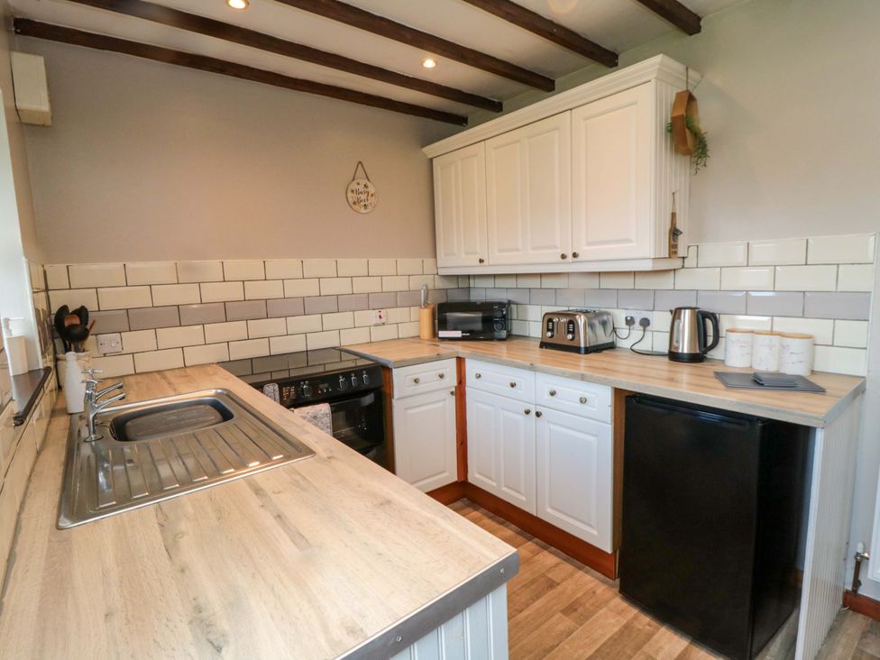 A kitchen with a sink, oven, toaster, kettle, and fridge at Stable Cottage in Staintondale near Burniston