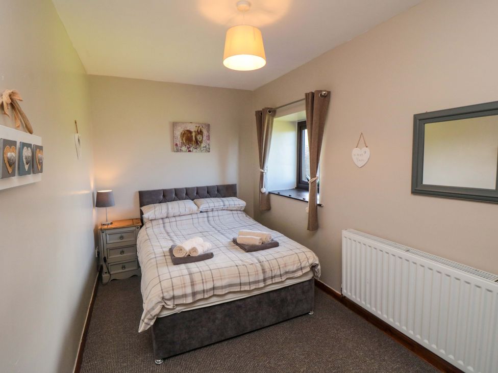 A bedroom with a bed and bedside table at Stable Cottage in Staintondale near Burniston