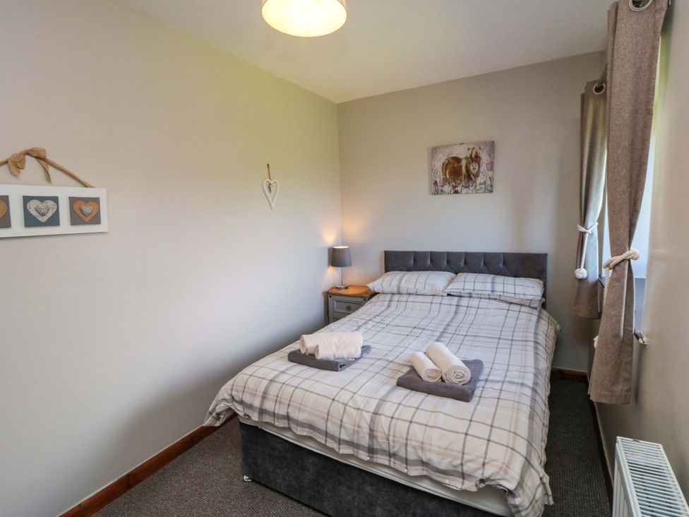 A bedroom with a double bed and bedside table at Stable Cottage in Staintondale near Burniston