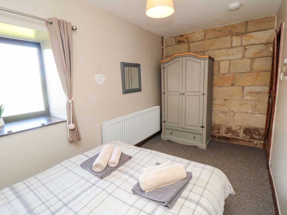 A bedroom with a bed and wardrobe at Stable Cottage Staintondale near Burniston