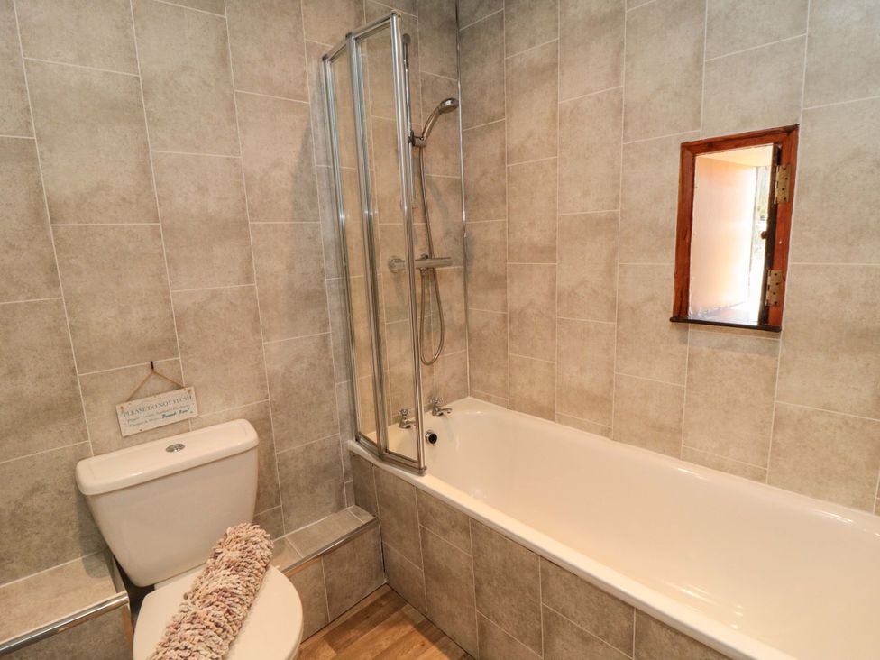 A bathroom with a bathtub and shower at Stable Cottage Staintondale near Burniston