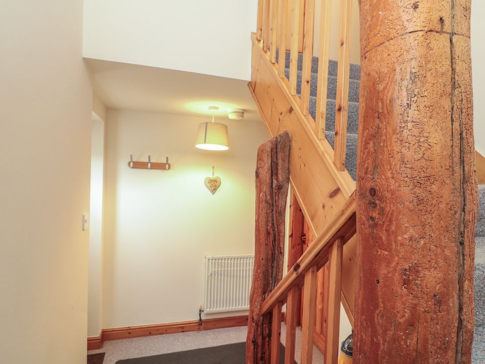 A staircase with wooden railing and wall hooks at Foxhunter Cottage in Hawsker near Whitby and Robin Hood's Bay