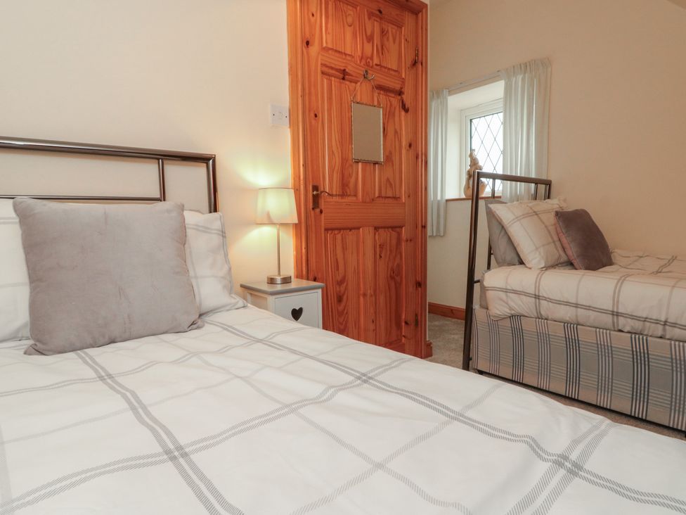 A bedroom with two beds, a lamp, and a wooden door at Foxhunter Cottage, Hawsker near Whitby and Robin Hood's Bay