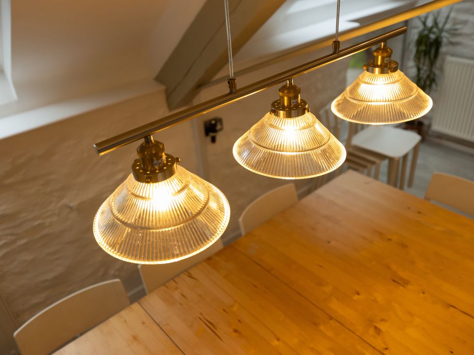 A dining room with pendant lights above a wooden table at The Coach House in Llangollen