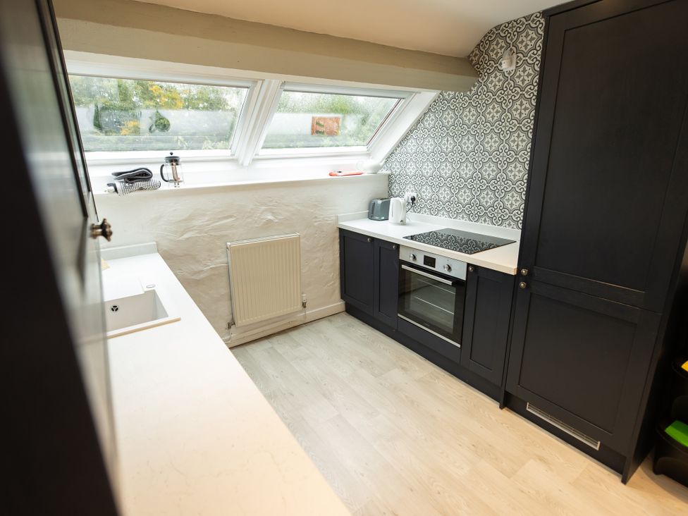 A kitchen with a sink, oven, and cooktop at The Coach House in Llangollen