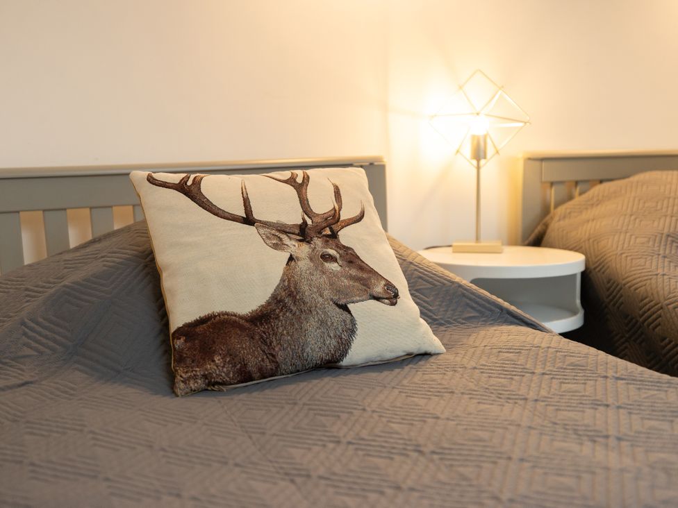 A bedroom with a deer print pillow and lamp at The Coach House Llangollen