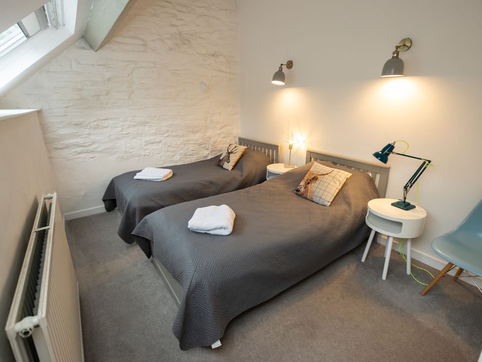 A bedroom with two single beds and decorative pillows at The Coach House in Llangollen