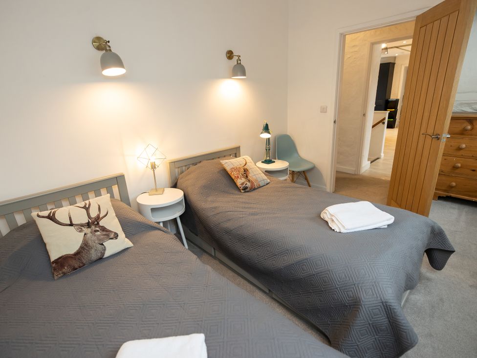 A bedroom with two beds and a door at The Coach House in Llangollen