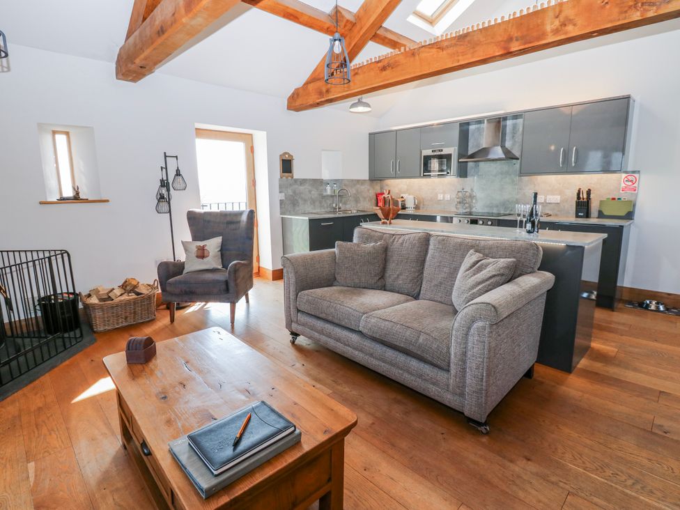 A living room with a sofa and kitchen area at Apple Tree Cottage near Bleatarn near Kirkby Stephen
