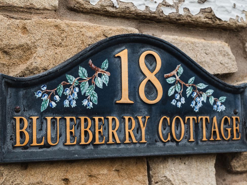 A sign for Blueberry Cottage featuring house number 18