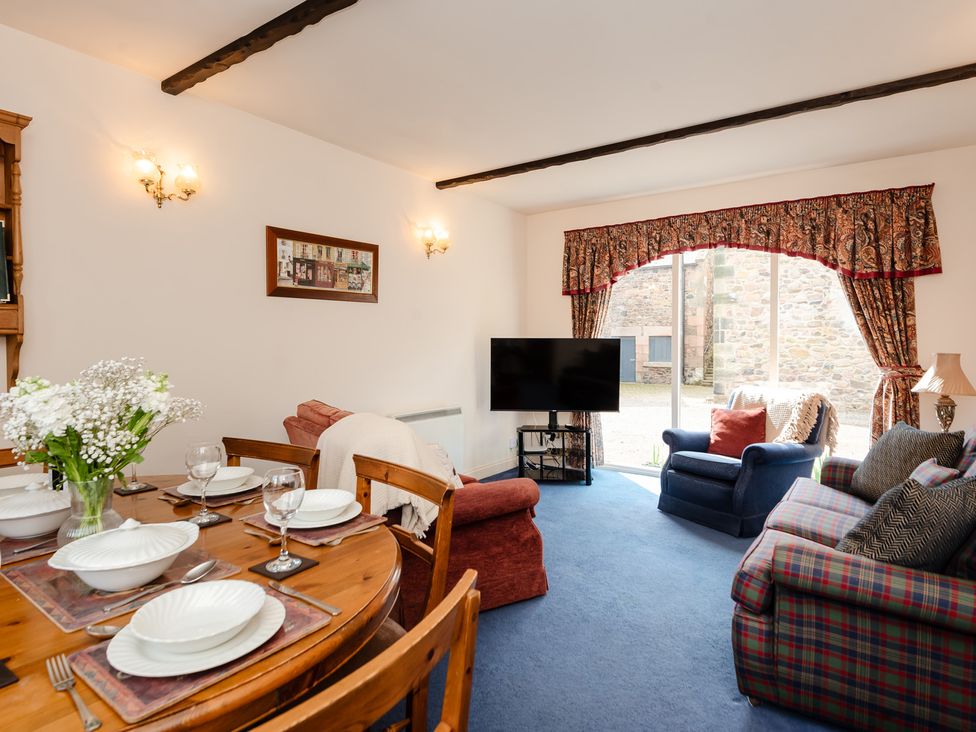 A living room with dining area and television at Blueberry Cottage in Akeld near Wooler