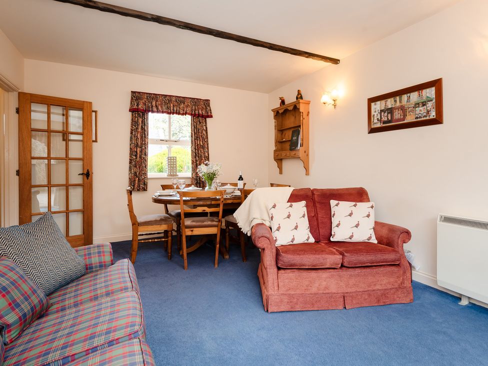 A living room with a sofa and dining area at Blueberry Cottage in Akeld near Wooler