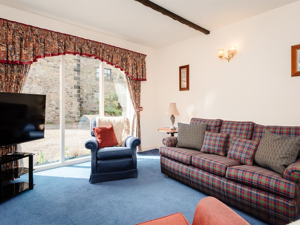 A living room with a sofa and television at Blueberry Cottage in Akeld near Wooler
