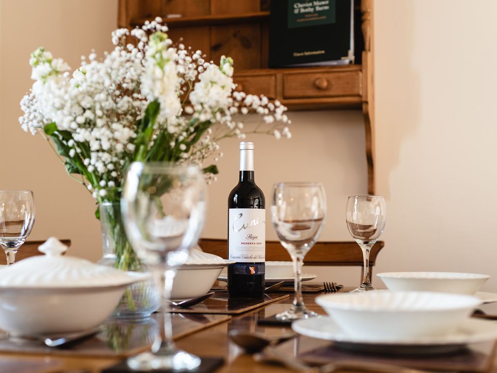A dining table set with dishes and a wine bottle at Blueberry Cottage in Akeld near Wooler