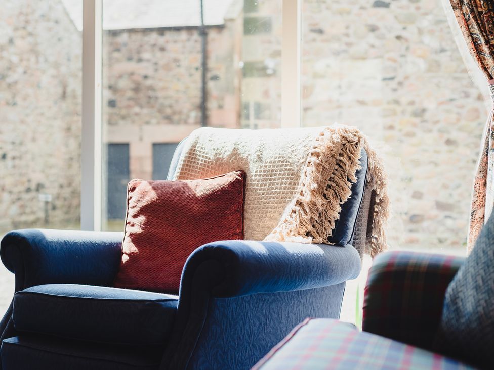 A living room with an armchair and a cushion at Blueberry Cottage Akeld near Wooler