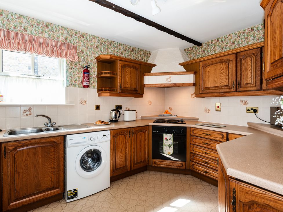 A kitchen with wooden cabinets and a washing machine at Blueberry Cottage Akeld near Wooler