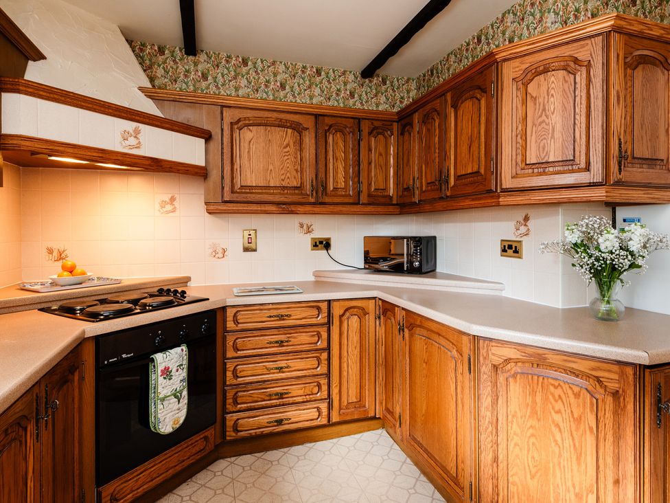 A kitchen with cabinets, countertop, and microwave at Blueberry Cottage in Akeld near Wooler