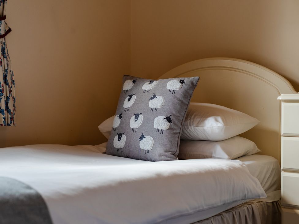 A bed with pillows and decorative sheep pillow at Blueberry Cottage Akeld near Wooler